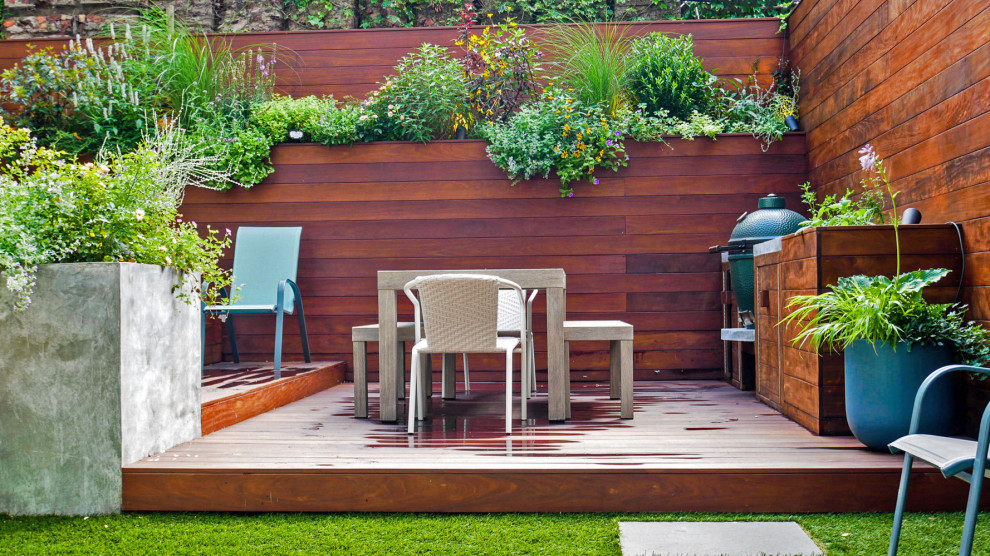 На фото: маленький солнечный участок и сад на заднем дворе в современном стиле с перегородкой для приватности, хорошей освещенностью и настилом для на участке и в саду