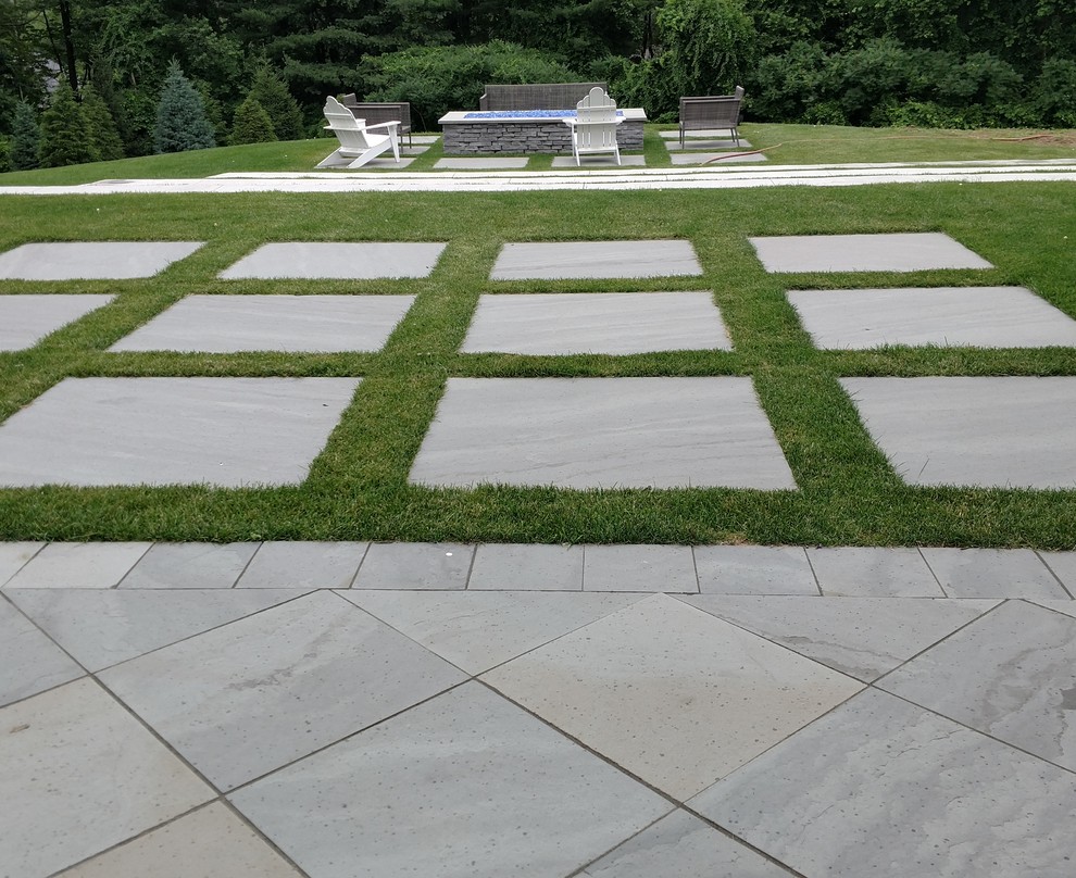 Immagine di un grande giardino design dietro casa con un focolare e pavimentazioni in pietra naturale