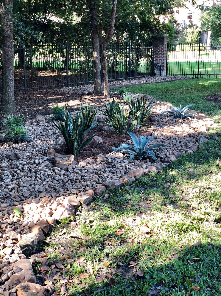This is an example of an eclectic back driveway partial sun garden in Houston.