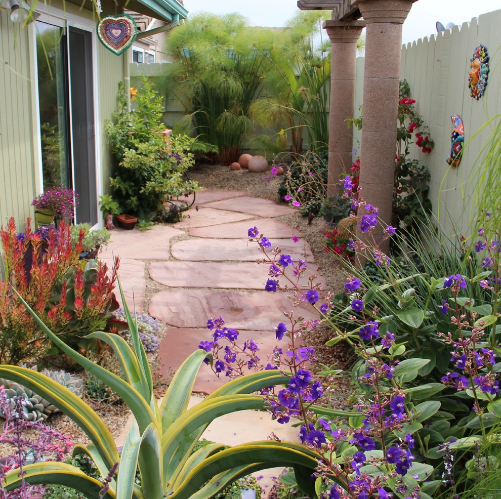 На фото: засухоустойчивый сад на заднем дворе в средиземноморском стиле с садовой дорожкой или калиткой и покрытием из каменной брусчатки