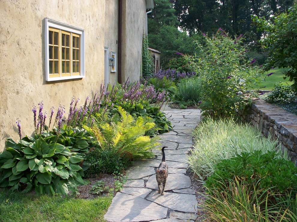 Aménagement d'un jardin latéral campagne avec une exposition ombragée et des pavés en pierre naturelle.