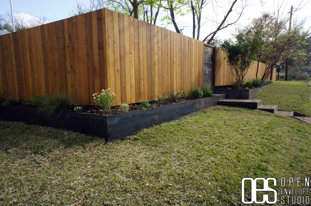 Ispirazione per un giardino moderno esposto a mezz'ombra di medie dimensioni e davanti casa in primavera con un muro di contenimento e pacciame