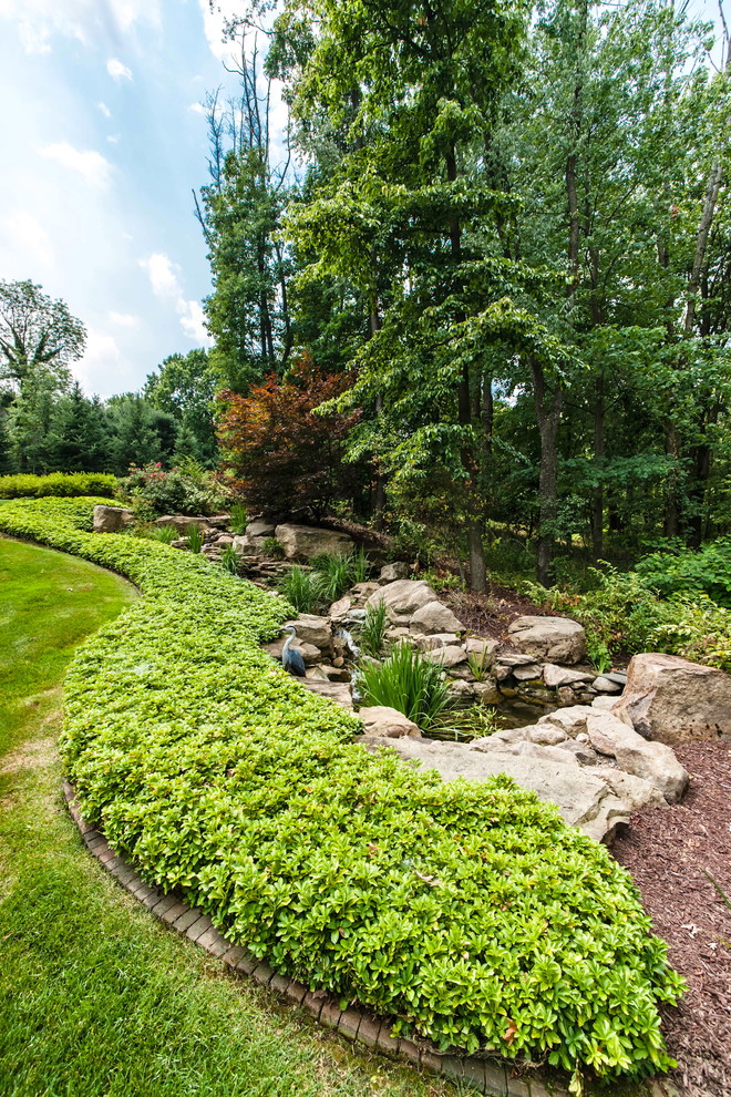 Diseño de jardín clásico extra grande en patio trasero con adoquines de ladrillo y roca decorativa