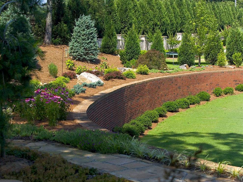 Photo of a mid-sized traditional backyard stone retaining wall landscape in Atlanta.