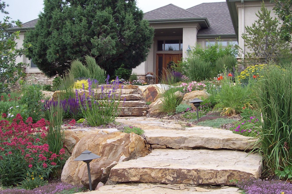 На фото: большой регулярный сад на заднем дворе в классическом стиле с покрытием из каменной брусчатки и подпорной стенкой