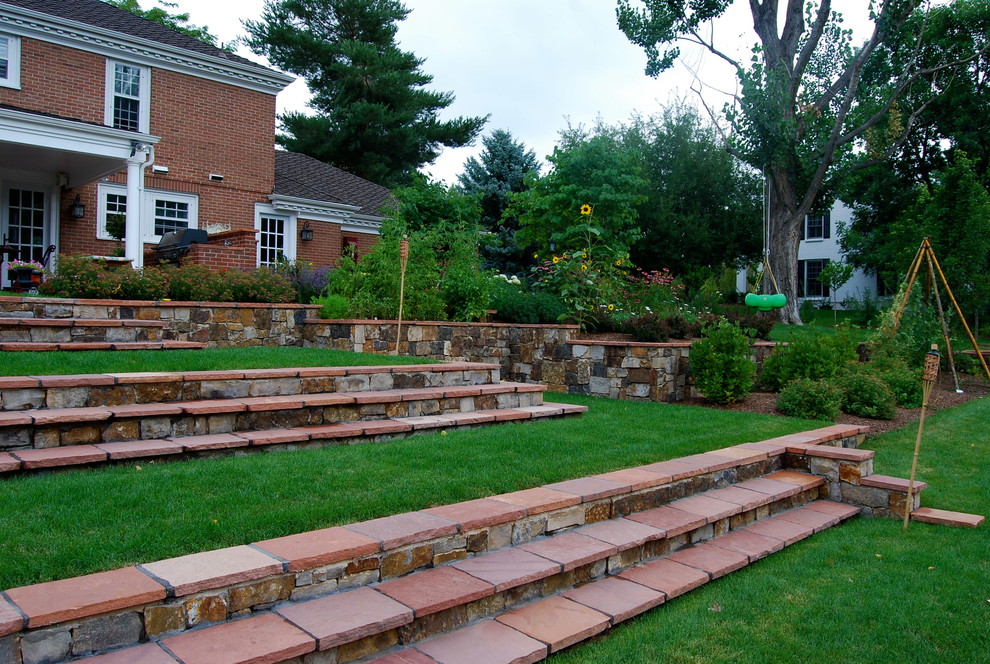 Idee per un grande giardino formale tradizionale dietro casa con pavimentazioni in pietra naturale e un muro di contenimento