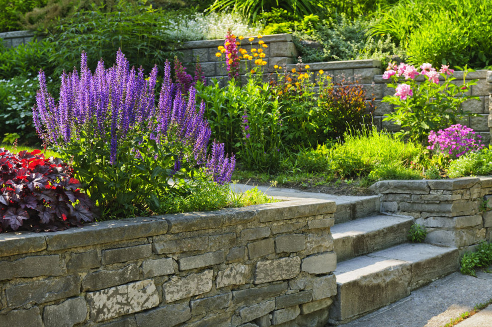 This is an example of a mid-sized traditional full sun backyard stone landscaping in Houston for summer.