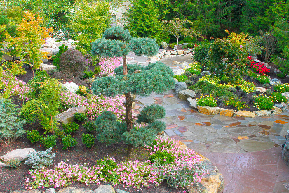 This is an example of a large classic back formal full sun garden for summer in Seattle with a potted garden and natural stone paving.