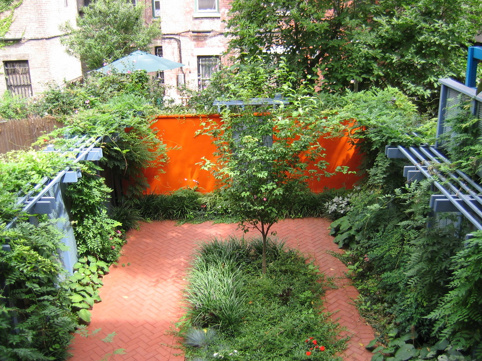 Photo of a mid-sized tropical partial sun backyard brick landscaping in New York for spring.