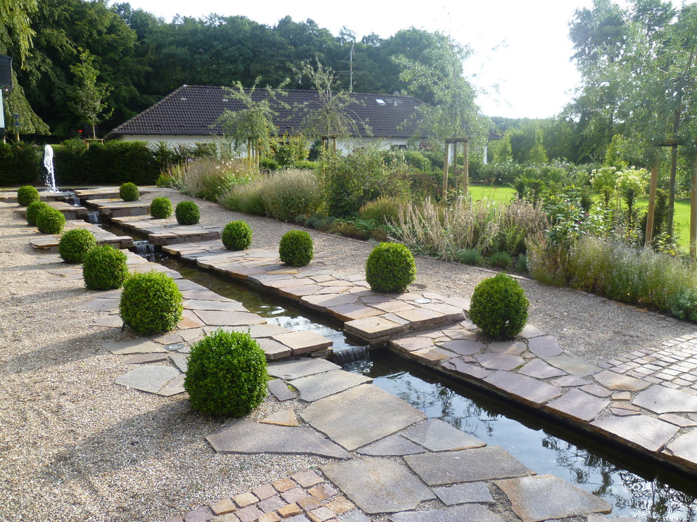 Photo of a large mediterranean full sun garden in Other with a water feature and gravel.