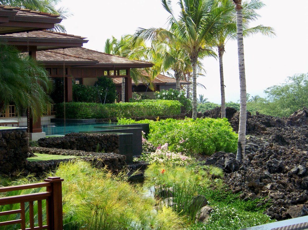 This is an example of a mid-sized tropical full sun backyard stone retaining wall landscape in Hawaii.