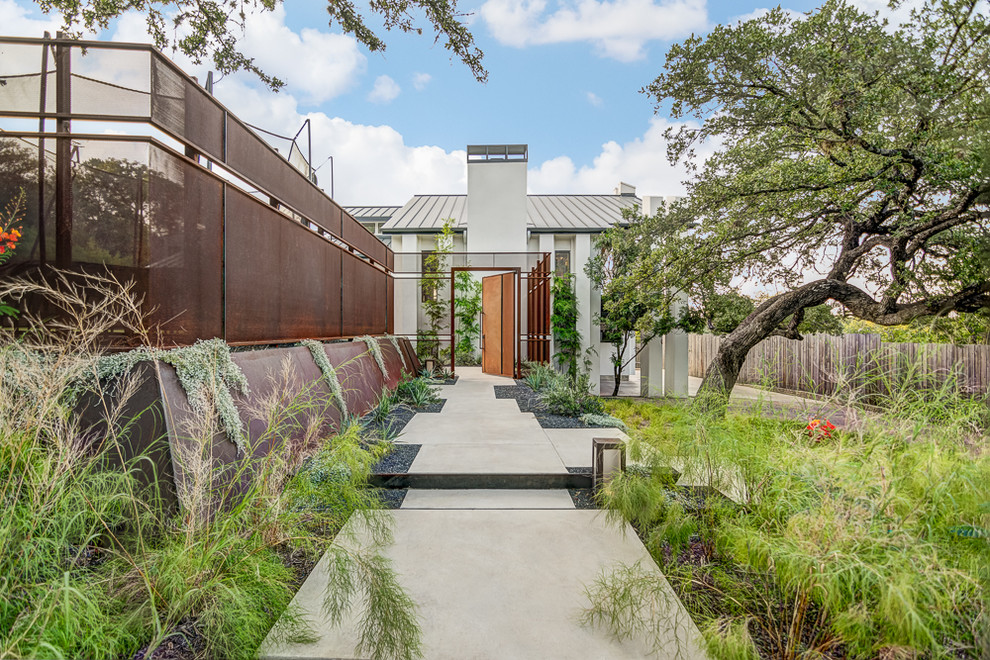 Aménagement d'un aménagement d'entrée ou allée de jardin avant contemporain avec des pavés en béton et une clôture en métal.