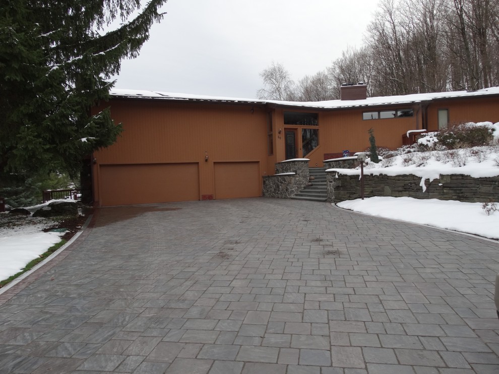 Exempel på en klassisk uppfart framför huset på vinteren, med en trädgårdsgång och marksten i betong