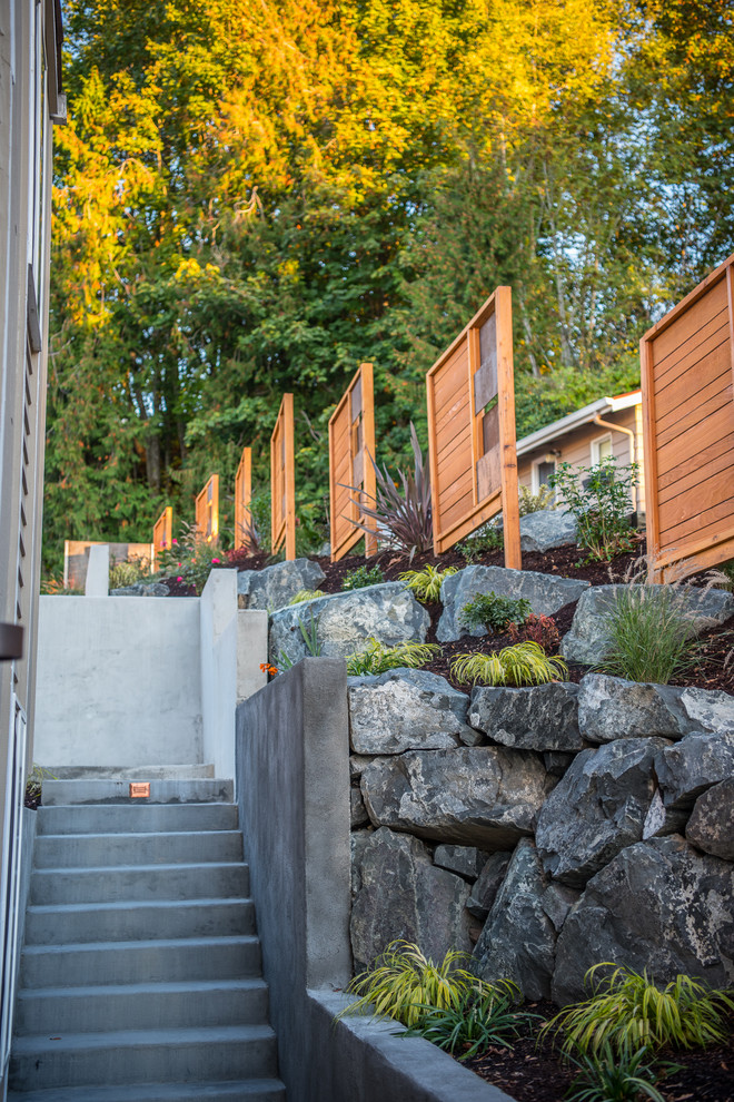Diseño de jardín moderno de tamaño medio en patio delantero con muro de contención y adoquines de hormigón