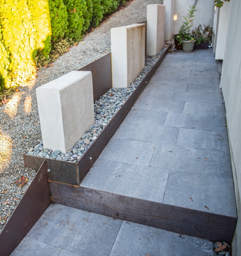 Ejemplo de jardín moderno de tamaño medio en patio delantero con muro de contención y adoquines de hormigón