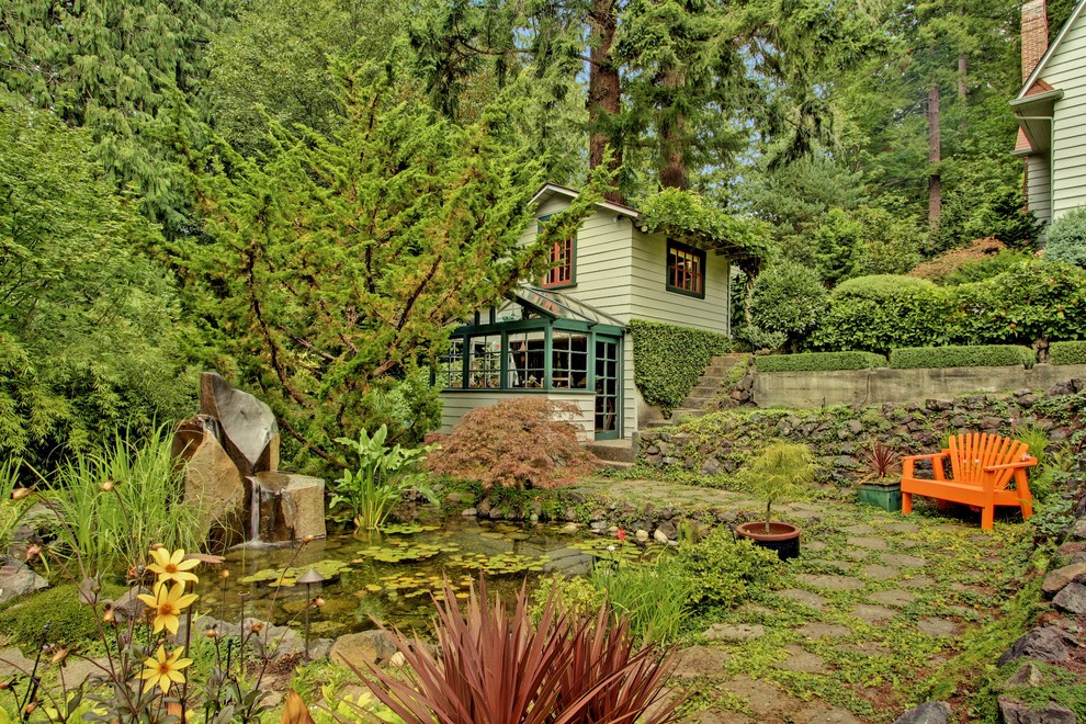 Foto på en stor lantlig trädgård, med en fontän och naturstensplattor