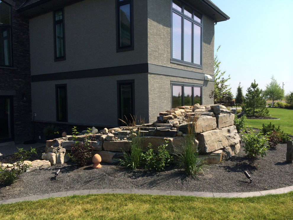 Großer Klassischer Gartenwasserfall hinter dem Haus mit Natursteinplatten in Calgary