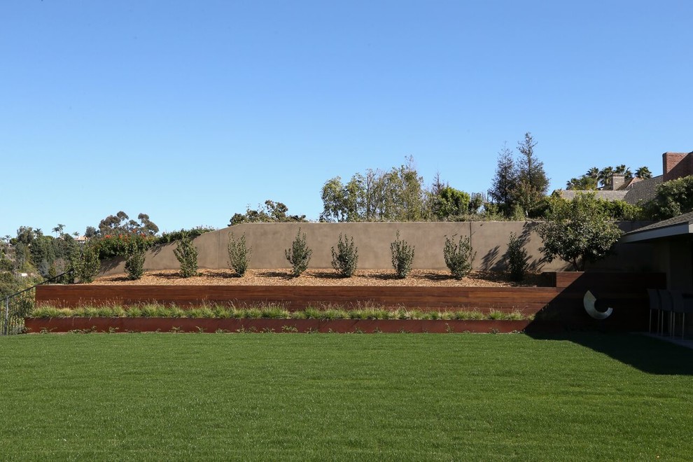 This is an example of a large contemporary drought-tolerant and full sun backyard mulch retaining wall landscape in Orange County for summer.