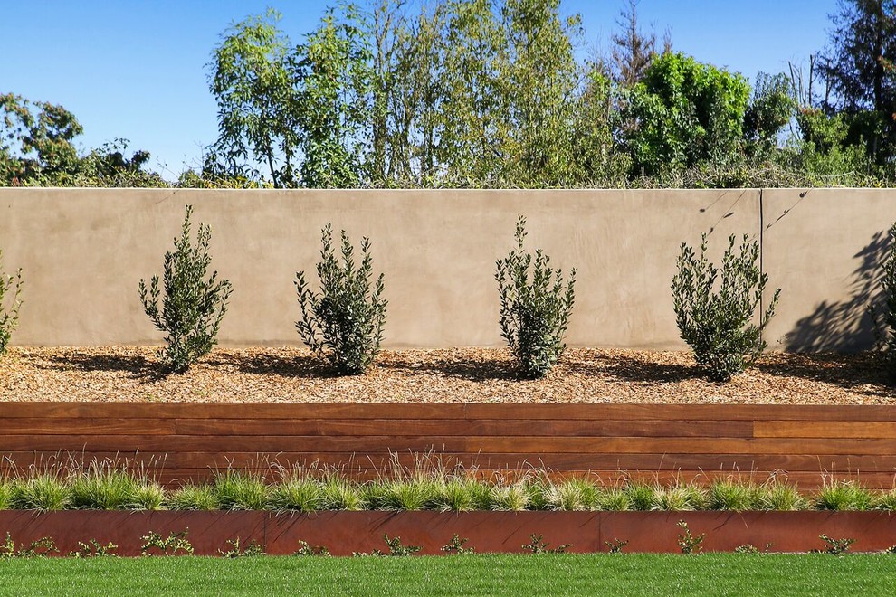 Foto di un grande giardino xeriscape design esposto in pieno sole dietro casa in estate con pacciame e un muro di contenimento
