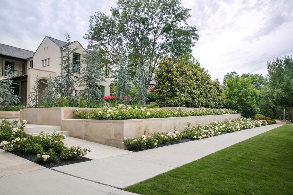 Foto di un giardino formale contemporaneo esposto in pieno sole di medie dimensioni e davanti casa in primavera con un muro di contenimento e ghiaia