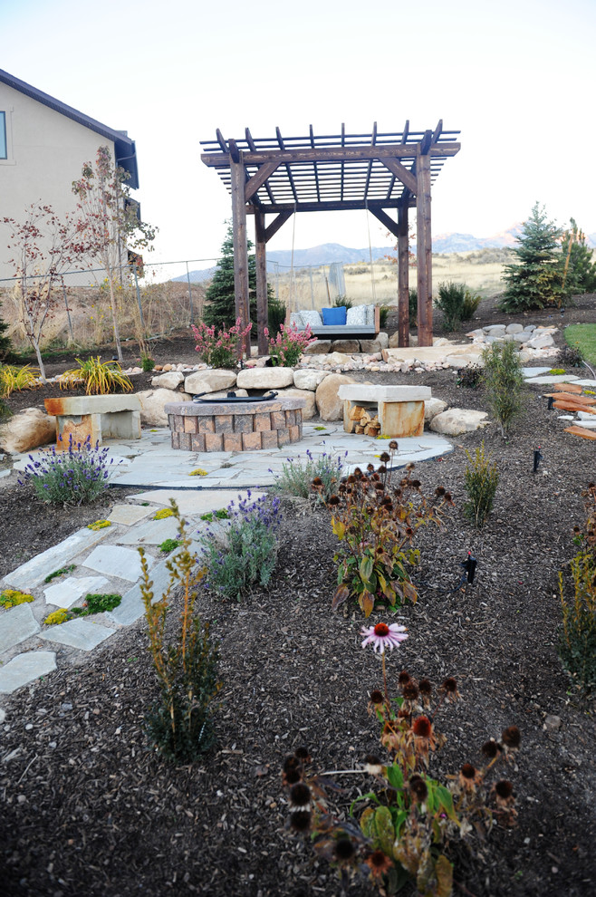 This is an example of a large modern sloped full sun garden for autumn in Salt Lake City with a water feature and natural stone paving.