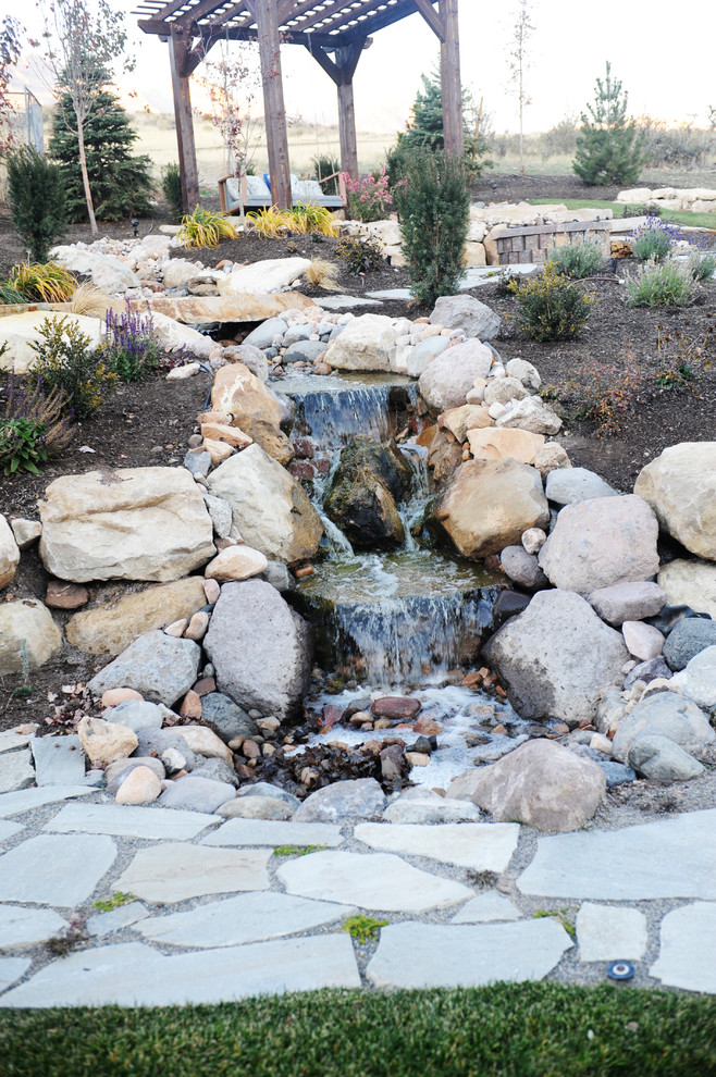 Immagine di un grande giardino minimalista esposto in pieno sole in autunno con un pendio, una collina o una riva, fontane e pavimentazioni in pietra naturale