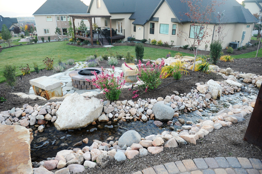 Large rustic sloped full sun garden for autumn in Salt Lake City with a water feature and brick paving.
