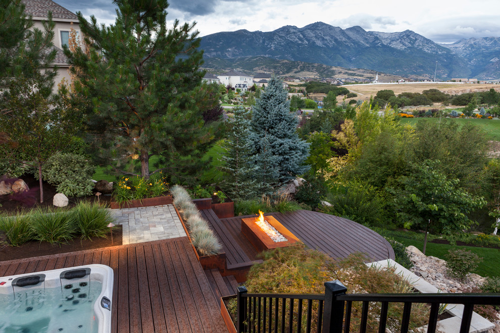 Photo of a mid-sized transitional partial sun backyard landscaping in Salt Lake City with a fire pit and decking for summer.