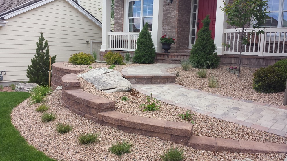 This is an example of a large classic front formal full sun garden for summer in Denver with a retaining wall and concrete paving.