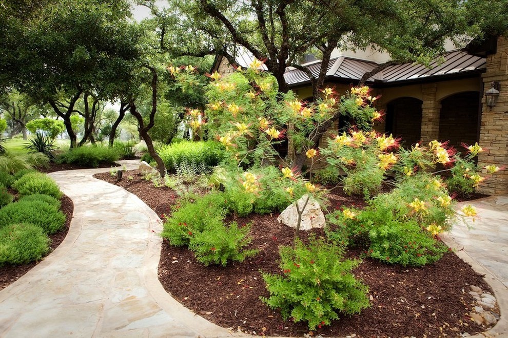 This is an example of a large traditional partial sun front yard stone landscaping in Austin for summer.