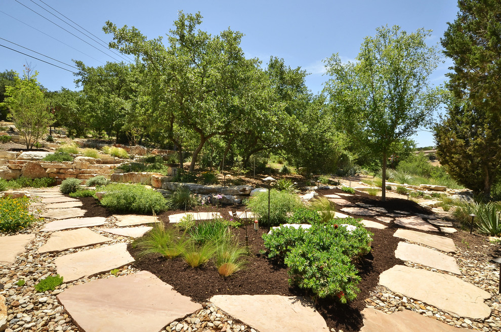 Inspiration for a large rustic sloped garden in Austin with a retaining wall and brick paving.