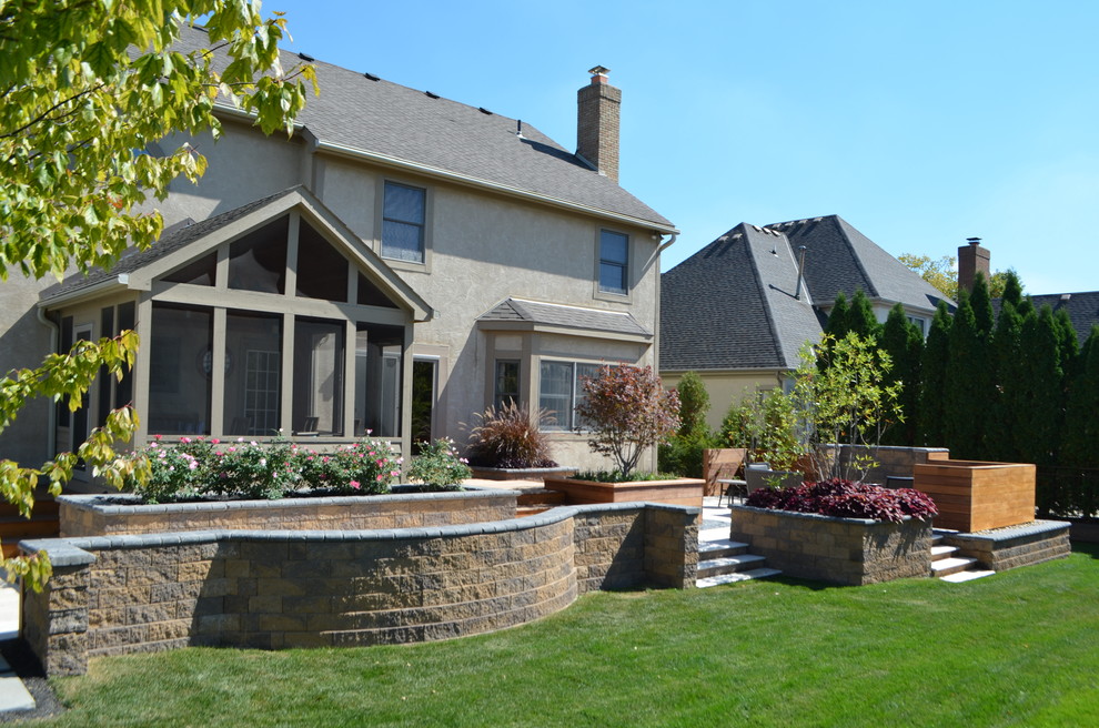 Стильный дизайн: солнечный, осенний засухоустойчивый сад среднего размера на заднем дворе в стиле модернизм с покрытием из каменной брусчатки, подпорной стенкой, хорошей освещенностью и с каменным забором - последний тренд