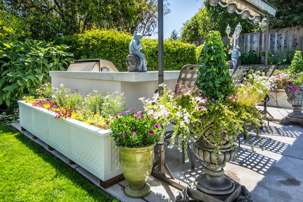 Modelo de jardín clásico de tamaño medio en verano en patio trasero con jardín de macetas, adoquines de hormigón y exposición total al sol