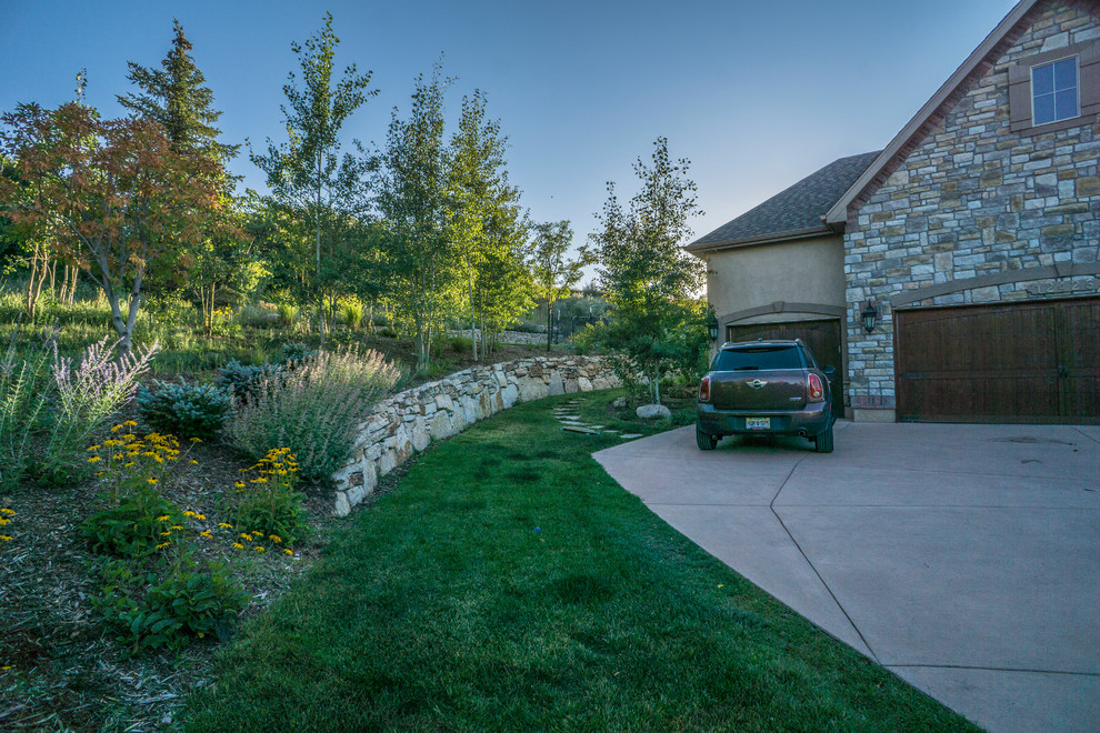 Large classic side xeriscape fully shaded garden for summer in Denver with a retaining wall and concrete paving.