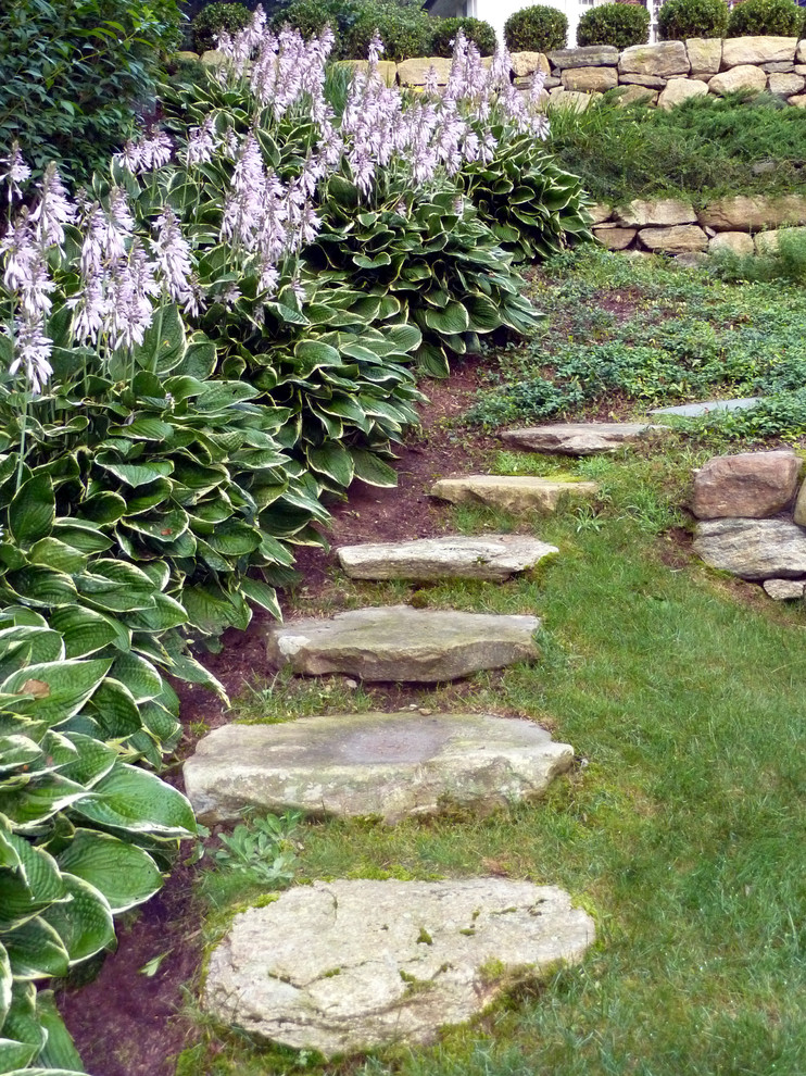 This is an example of a large traditional full sun backyard gravel retaining wall landscape in Boston.