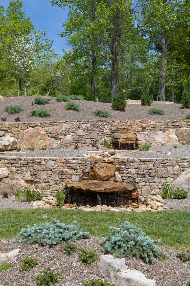 This is an example of an expansive classic back xeriscape partial sun garden for summer in Other with a retaining wall and natural stone paving.