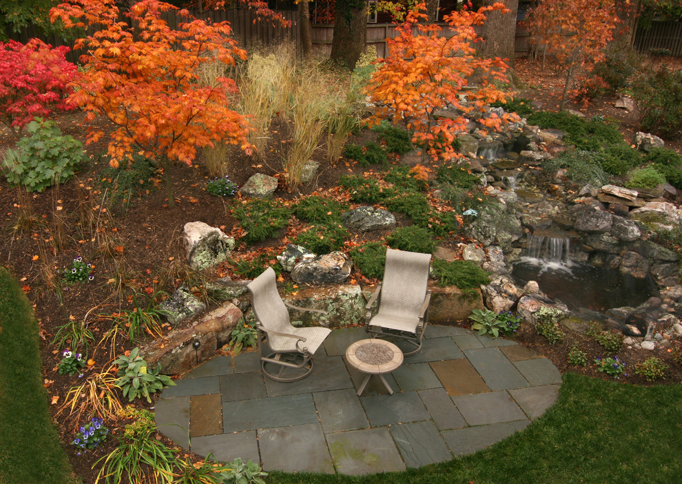 Immagine di un giardino design esposto a mezz'ombra di medie dimensioni in autunno con fontane, un pendio, una collina o una riva e pavimentazioni in pietra naturale