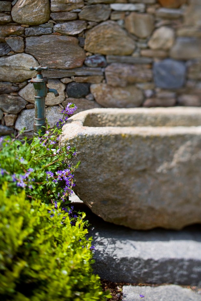 Immagine di un ampio giardino formale country esposto in pieno sole dietro casa in estate con fontane e pavimentazioni in pietra naturale