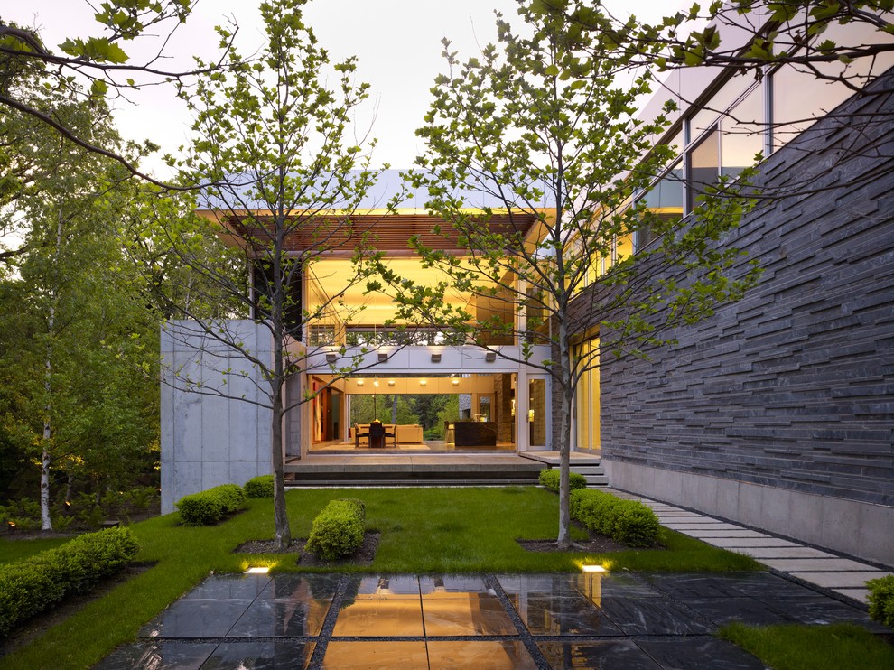 Cette image montre un jardin arrière minimaliste avec une exposition partiellement ombragée et des pavés en pierre naturelle.