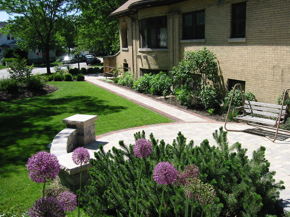 Inspiration för en mellanstor amerikansk formell trädgård i delvis sol framför huset, med en trädgårdsgång och naturstensplattor