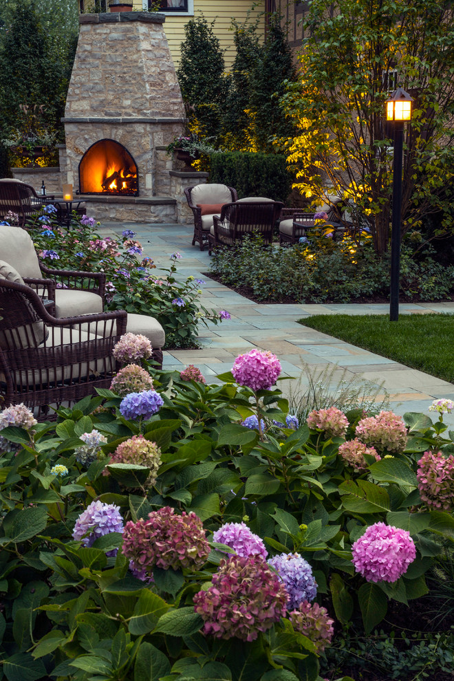 Inspiration for a large classic back formal partial sun garden in Chicago with natural stone paving and a fireplace.