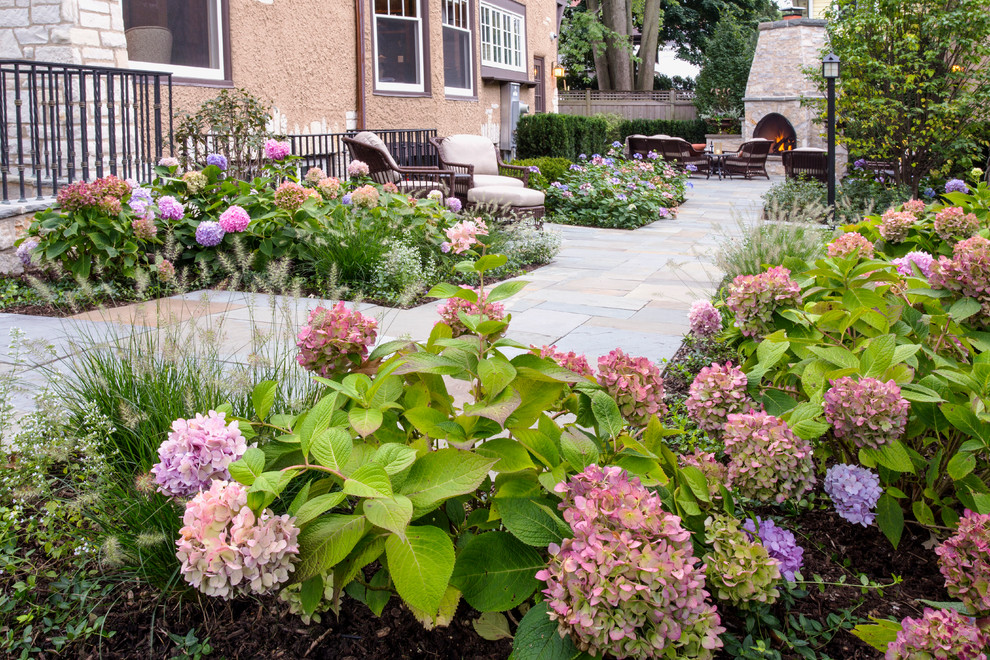 Imagen de jardín clásico grande en patio trasero con adoquines de piedra natural, jardín francés, brasero y exposición parcial al sol