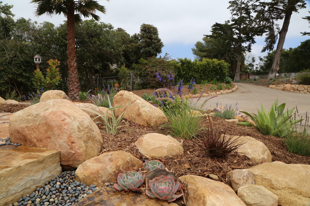 Großer Mediterraner Garten hinter dem Haus mit direkter Sonneneinstrahlung und Natursteinplatten in Santa Barbara