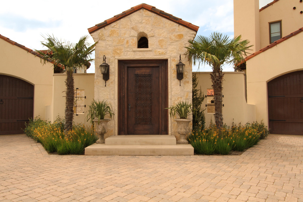 Ispirazione per un ampio vialetto d'ingresso mediterraneo esposto in pieno sole davanti casa con un muro di contenimento e pavimentazioni in pietra naturale