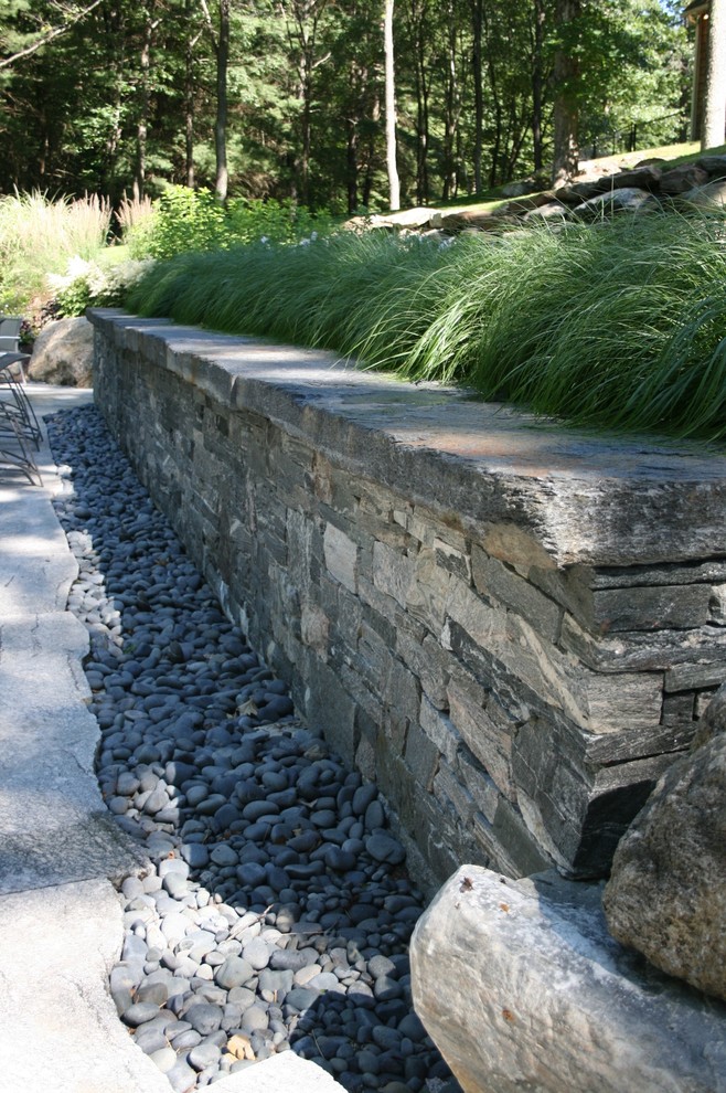 Photo of a large eclectic partial sun backyard stone retaining wall landscape in Boston for spring.