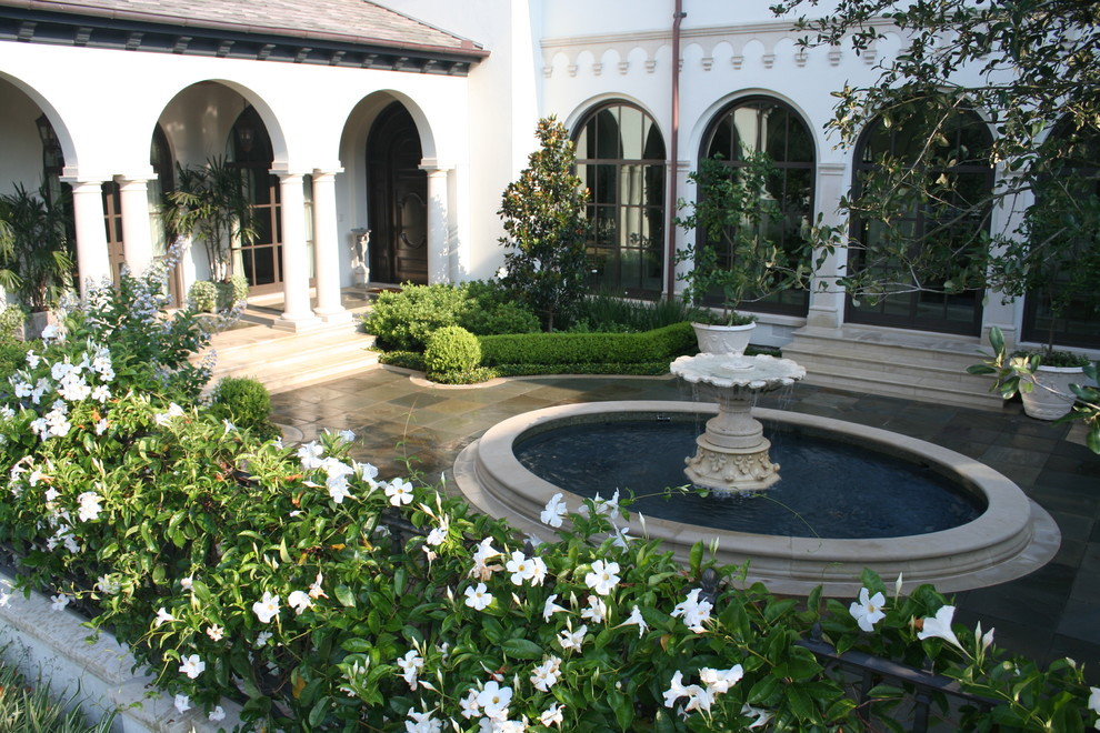 Imagen de jardín mediterráneo en patio con fuente, adoquines de piedra natural, jardín francés y exposición total al sol