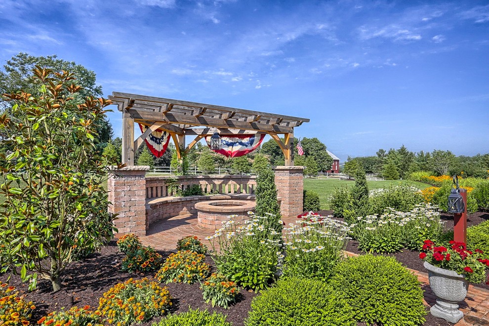 Foto di un grande giardino formale country esposto in pieno sole in cortile con un focolare e pavimentazioni in mattoni