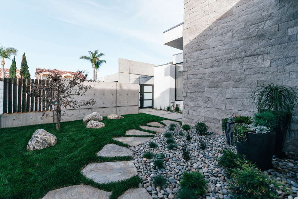 Ispirazione per un giardino etnico esposto a mezz'ombra in cortile e di medie dimensioni con pavimentazioni in pietra naturale e recinzione in metallo