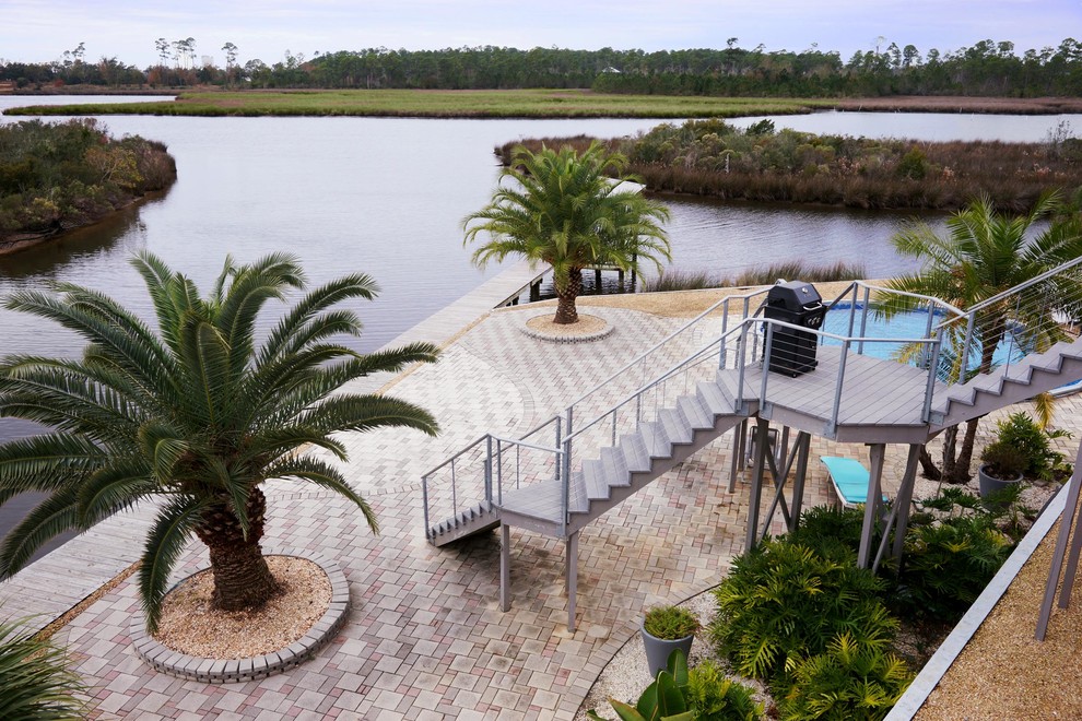 This is an example of a beach style back full sun garden in New Orleans with natural stone paving.