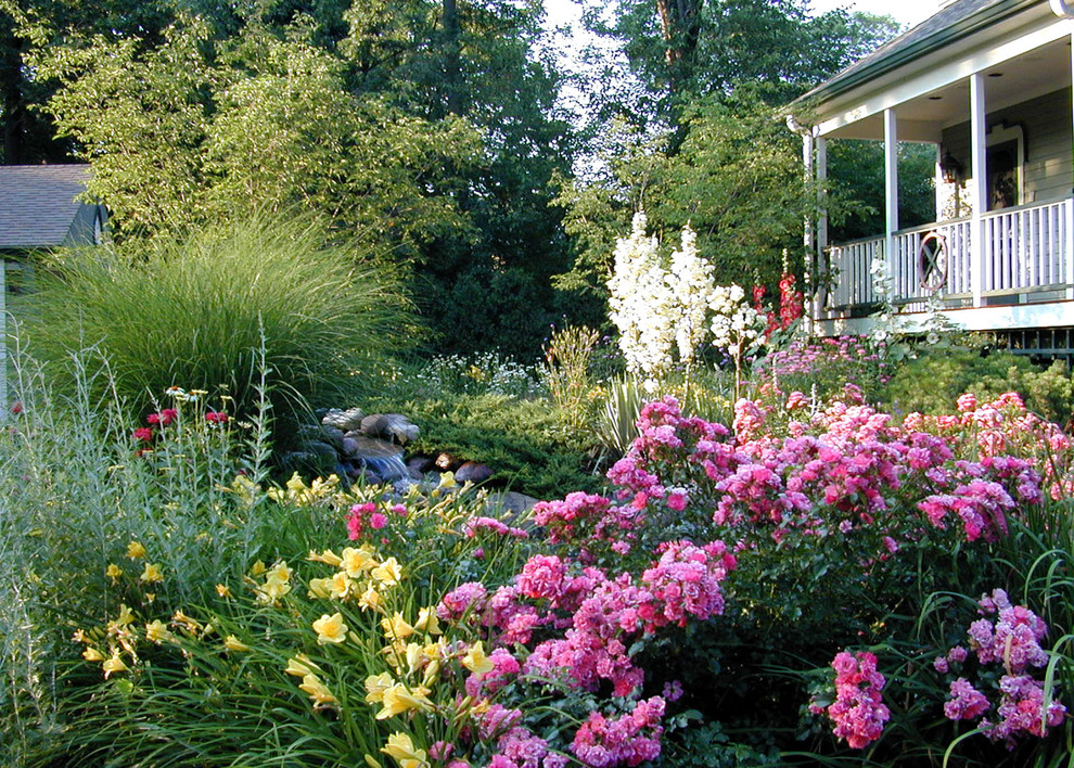 Diseño de jardín clásico en verano en patio trasero con fuente y exposición parcial al sol